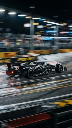 Black Formula 1 race car racing on wet night street circuit