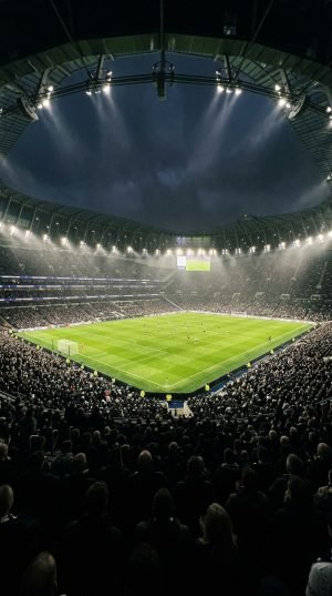 Wide angle view of packed football stadium under floodlights at night